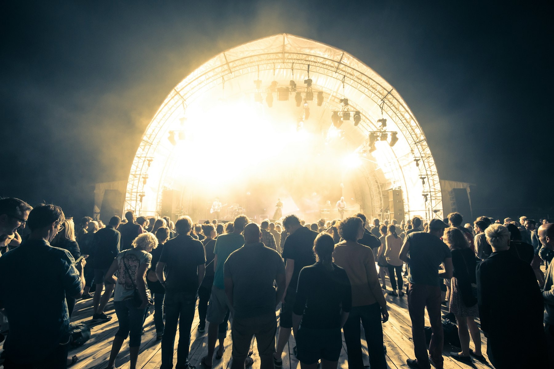 Crowd facing a brightly lit arched stage